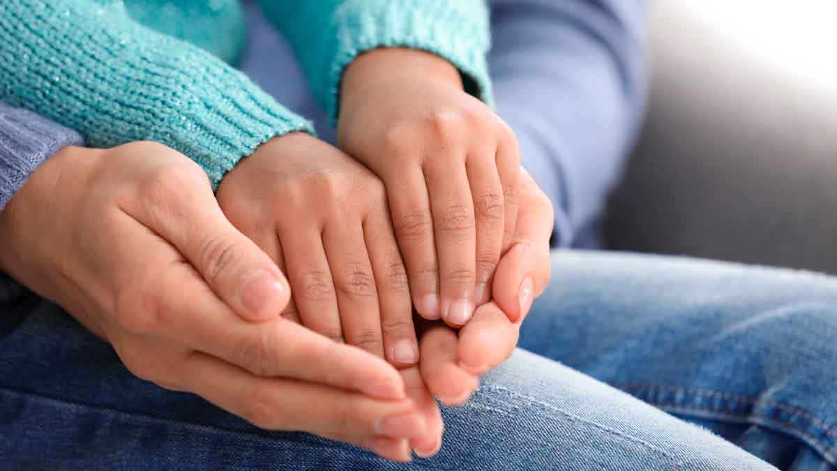 Manos de un adulto sosteniendo las de un niño, símbolo de la adopción en la Comunidad de Madrid 2025