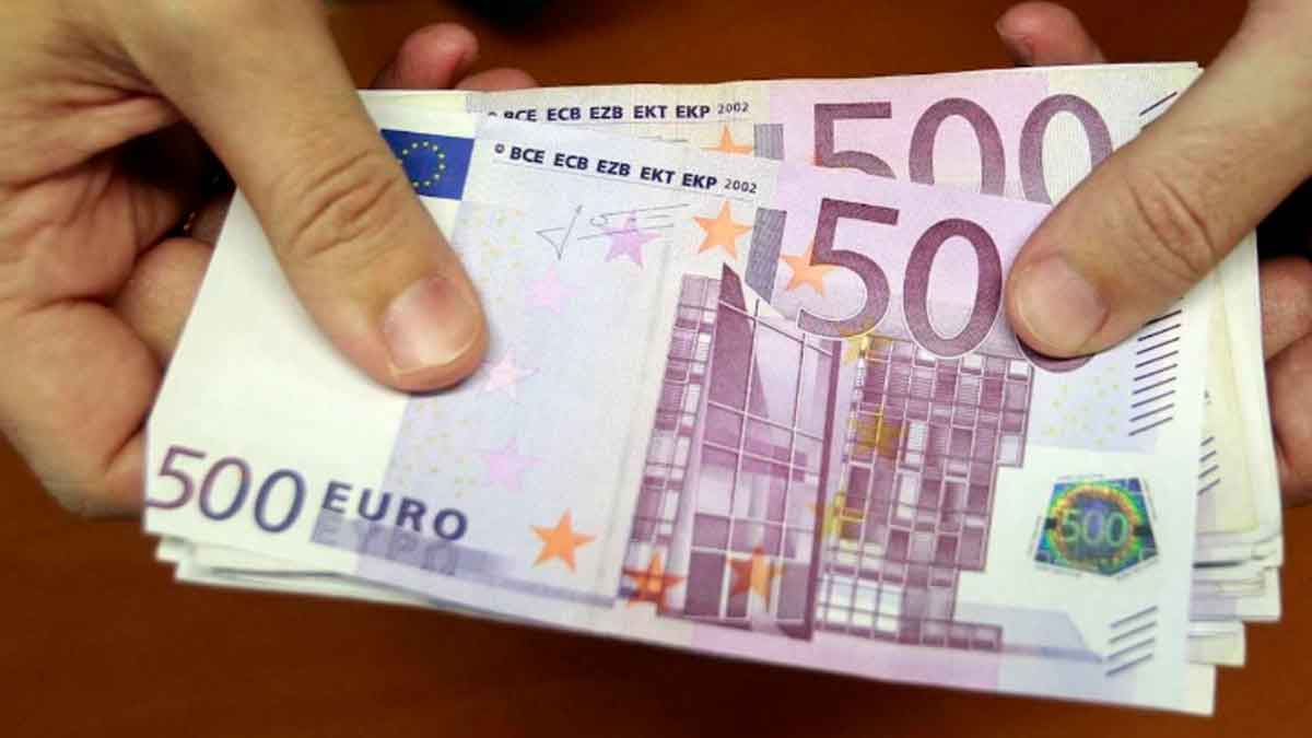 Billetes de 500 € en manos, representando la ayuda de 10.980 € del SEPE para desempleados con cotización insuficiente