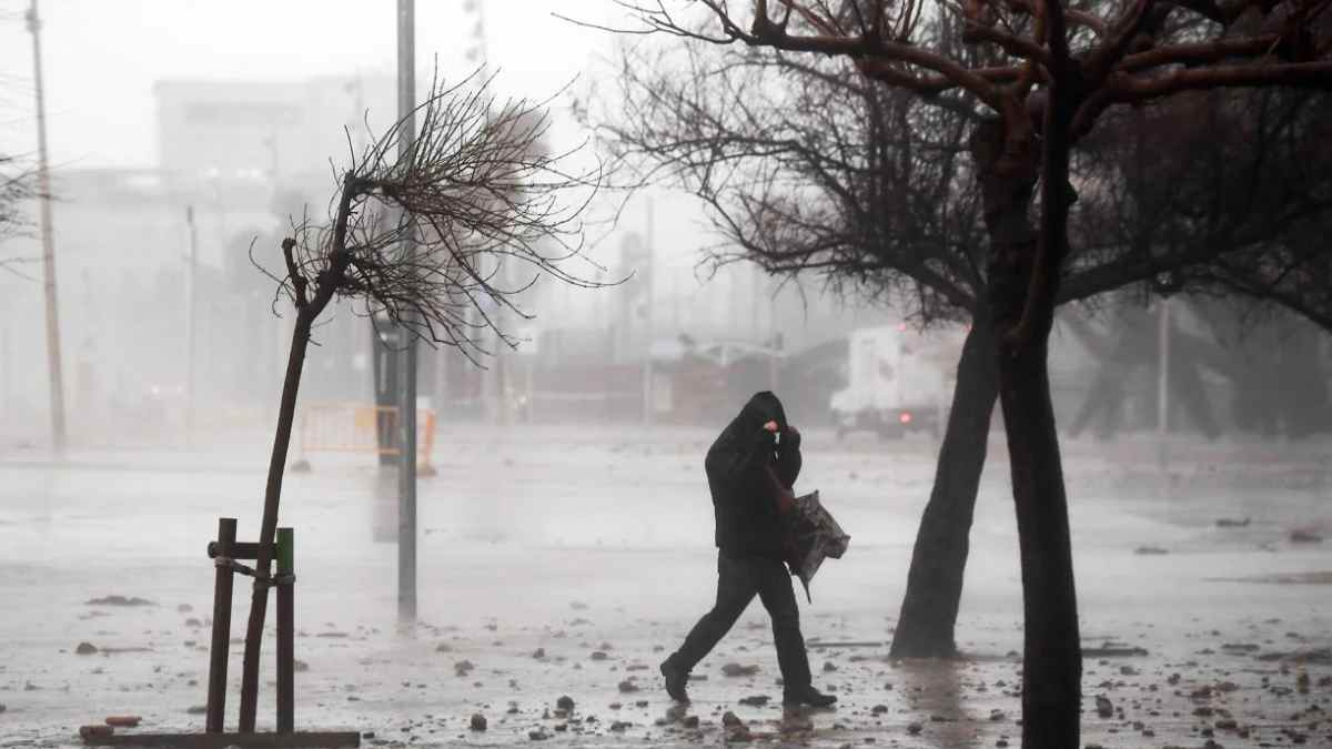 hombre caminando bajo tormenta en madrid con viento fuerte y lluvia.