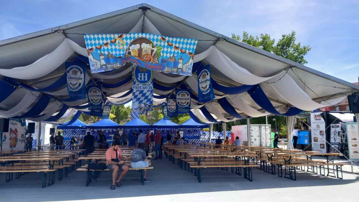 Carpa bávara de la Oktoberfest en Vallecas Madrid con mesas de madera y decoración alemana.