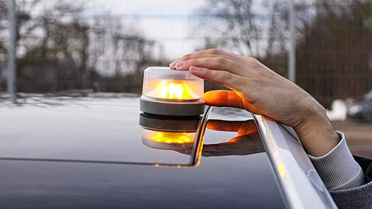 Conductor colocando luz de emergencia V16 en el techo del coche.