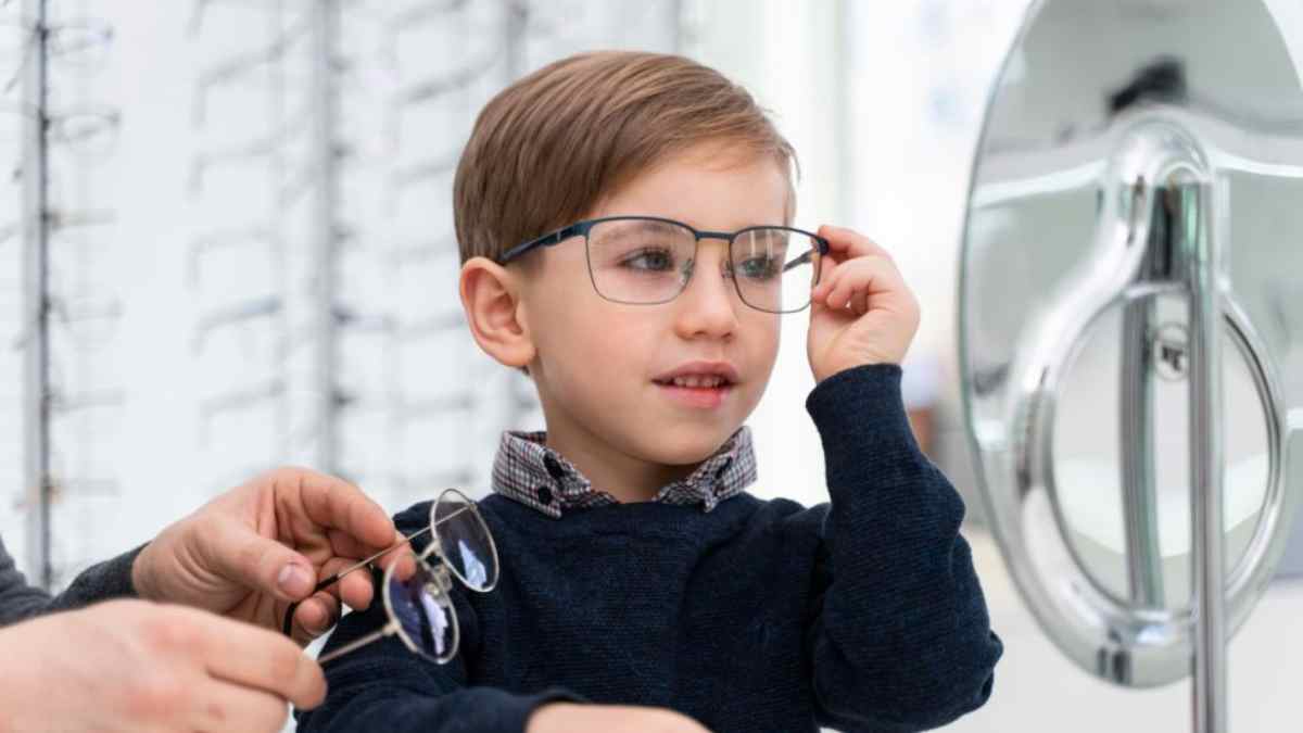 Niño probándose gafas en óptica por la ayuda de 100 euros para gafas infantiles en España.