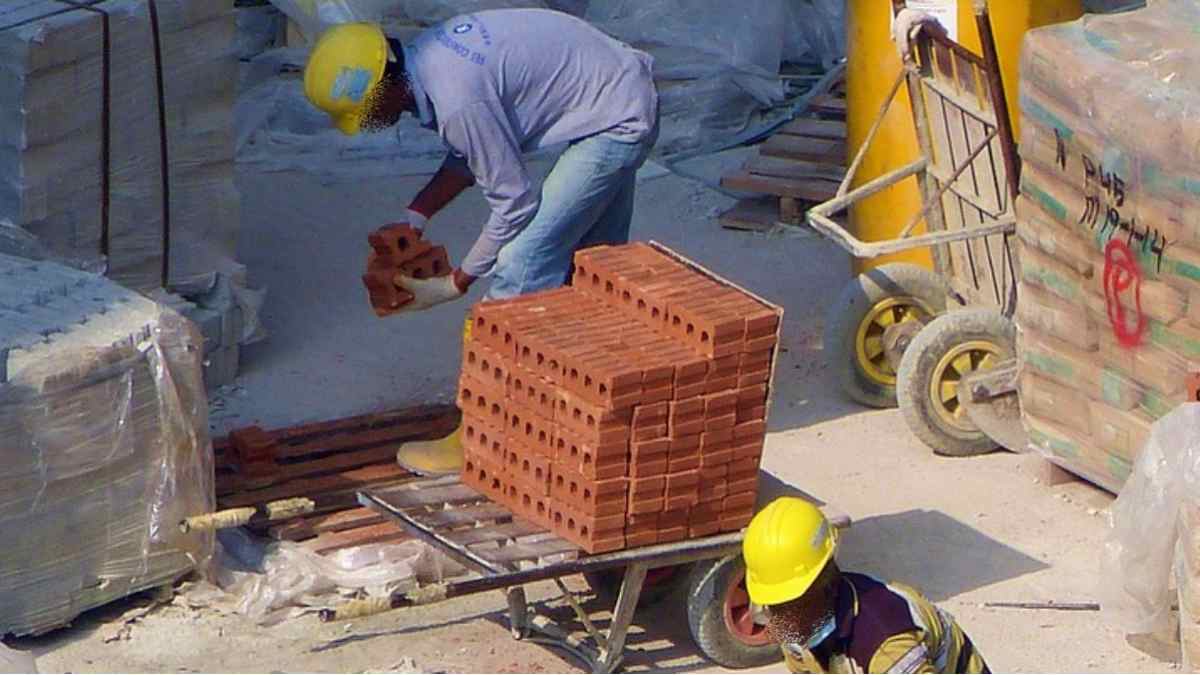 Trabajadores de la construcción manipulando ladrillos en una obra.