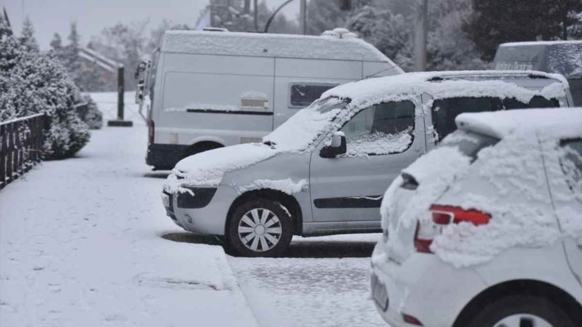 Coches cubiertos de nieve en una calle de Madrid durante la llegada del frente polar con heladas.