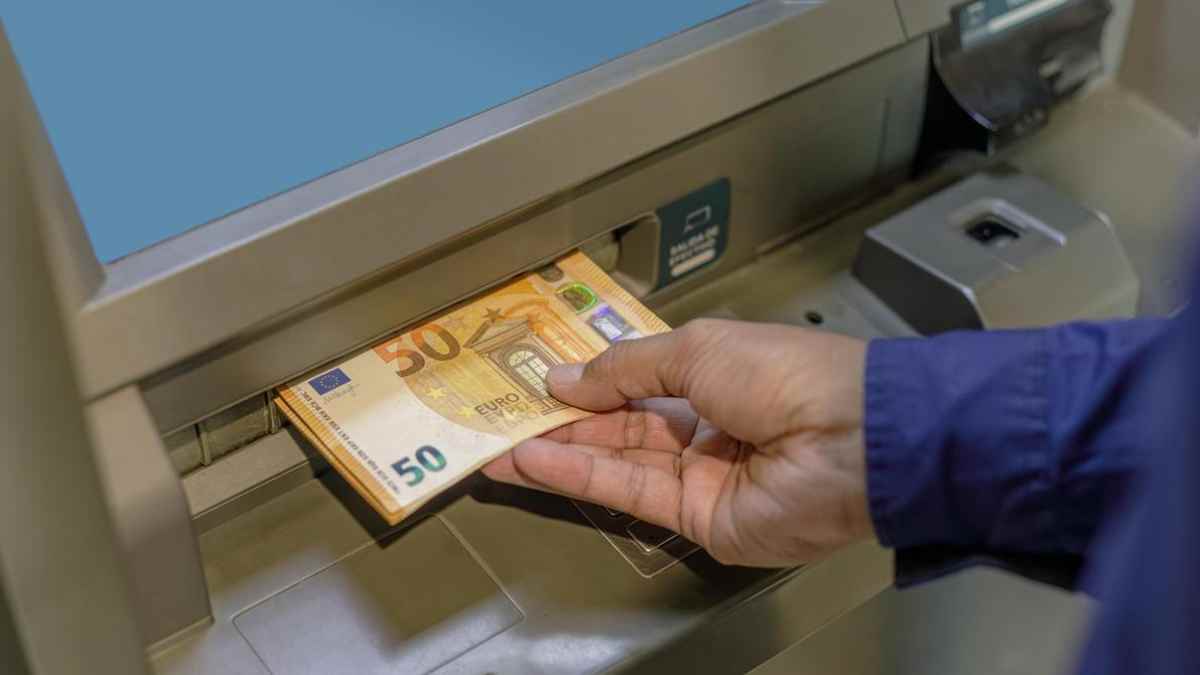 mano retirando billetes de 50 euros en un cajero automático.