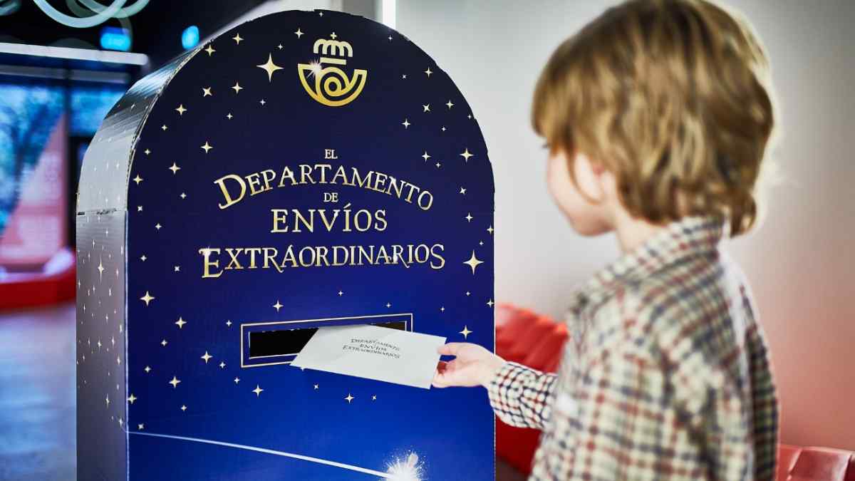 Niño depositando una carta en un buzón mágico de Correos para envíos navideños.