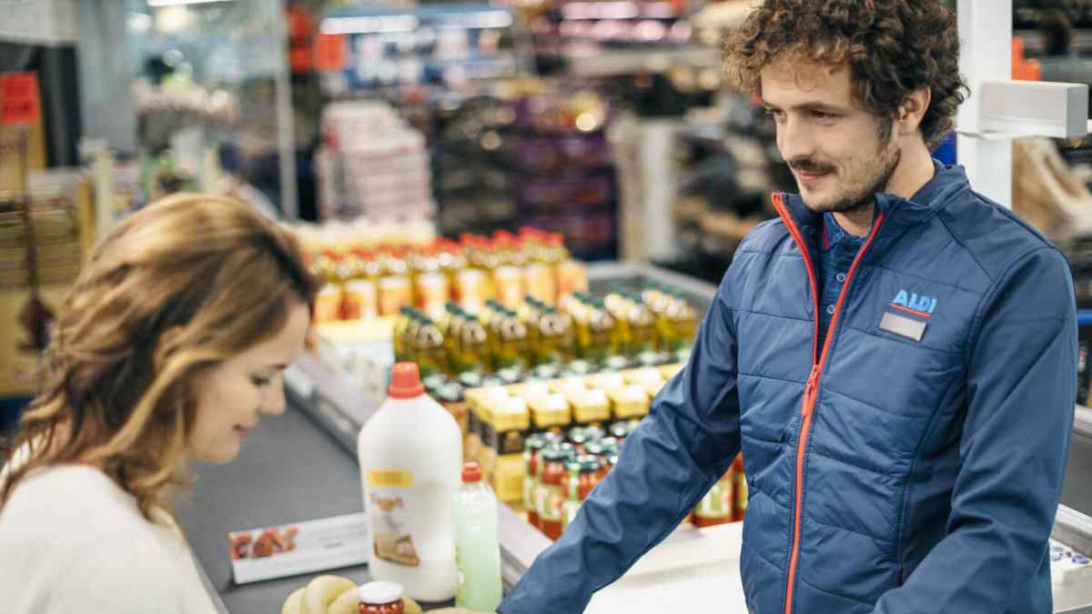 Empleado de supermercado atendiendo a una clienta en la caja de una tienda en Madrid.