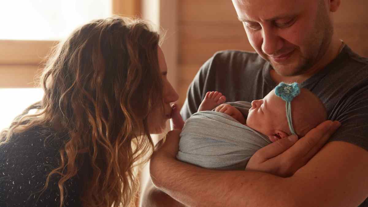 Padres sosteniendo a su bebé recién nacido envuelto en una manta.