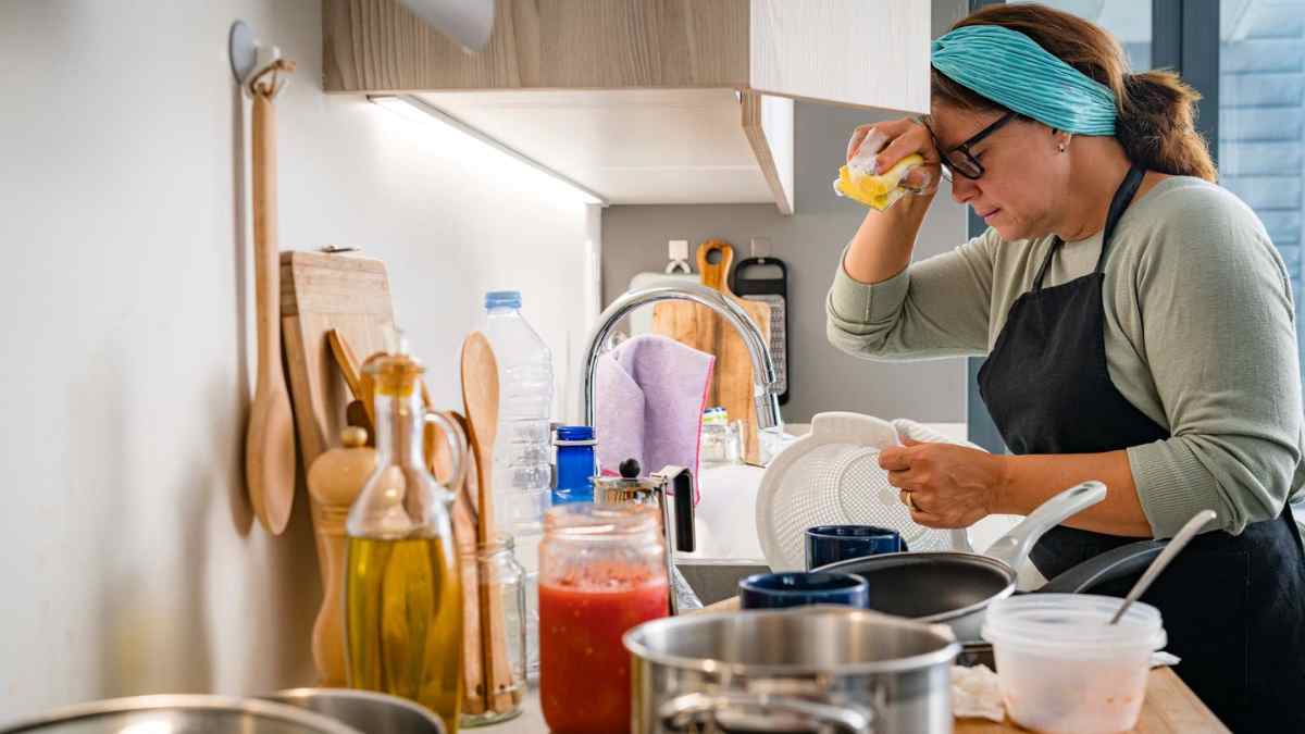 Ama de casa realizando tareas domésticas en su cocina mientras puede acceder a un subsidio del SEPE.