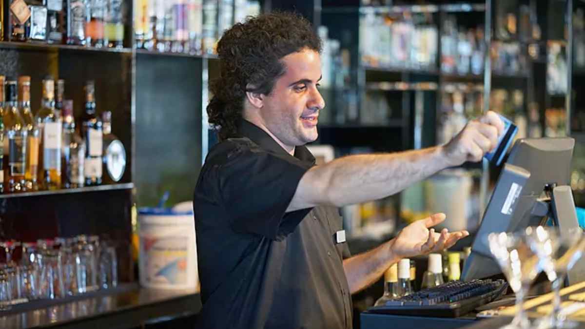 Trabajador sirviendo copas en un pub durante una baja médica por sepsis