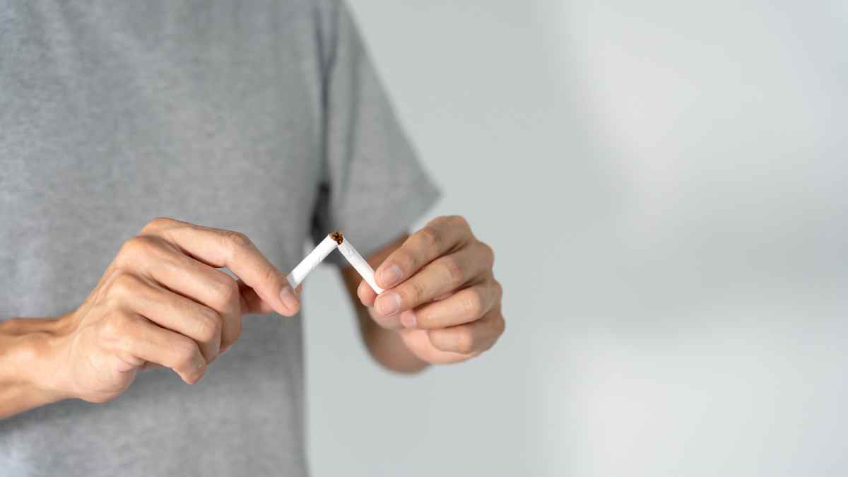 Persona rompiendo un cigarrillo para dejar de fumar con ayuda gratuita en Madrid