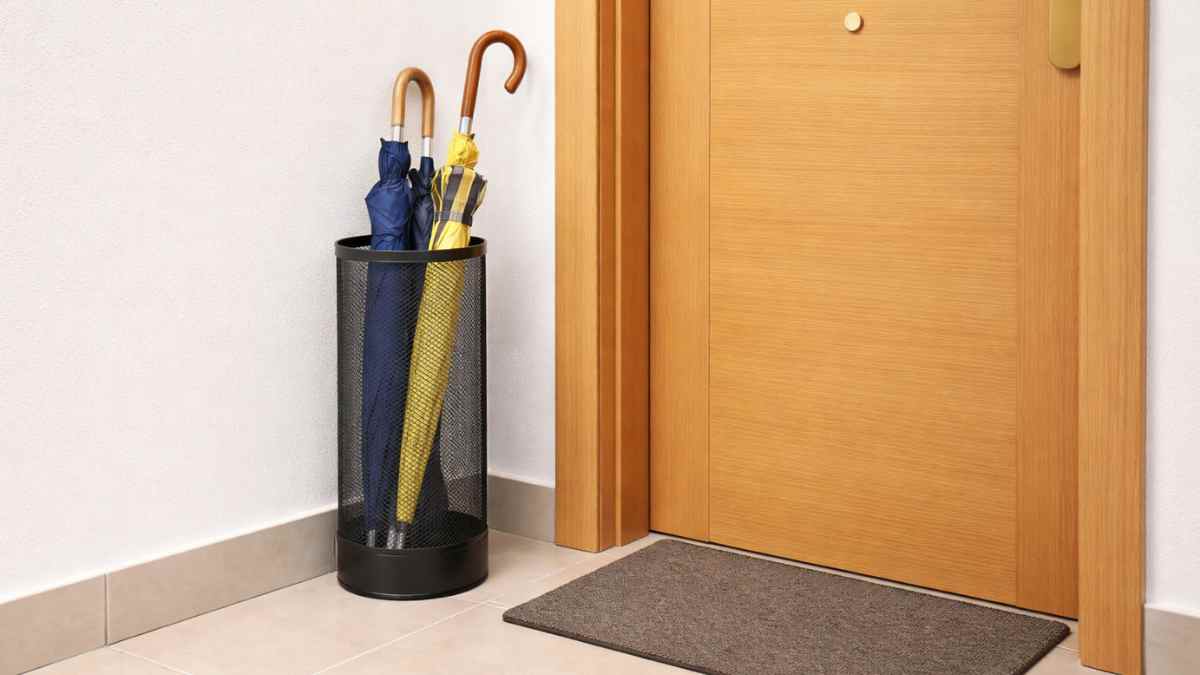 Paraguero en el rellano junto a la puerta de un piso en edificio de vecinos