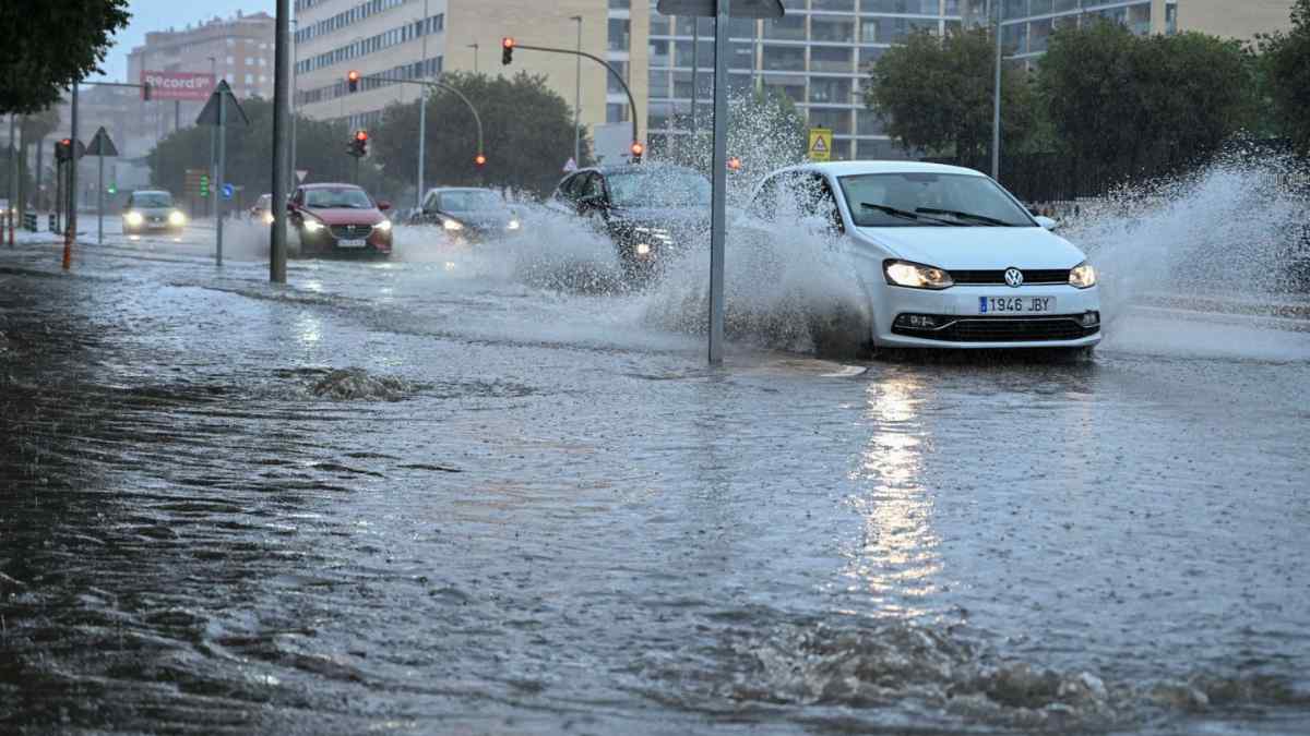 Coches circulando por una calle inundada en Madrid durante fuertes lluvias tras el aviso de AEMET