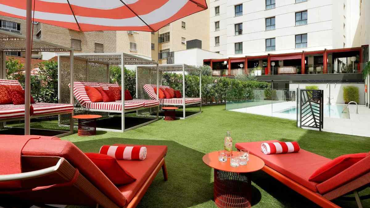 Piscina de hotel en Madrid con camas balinesas y zona de descanso al aire libre