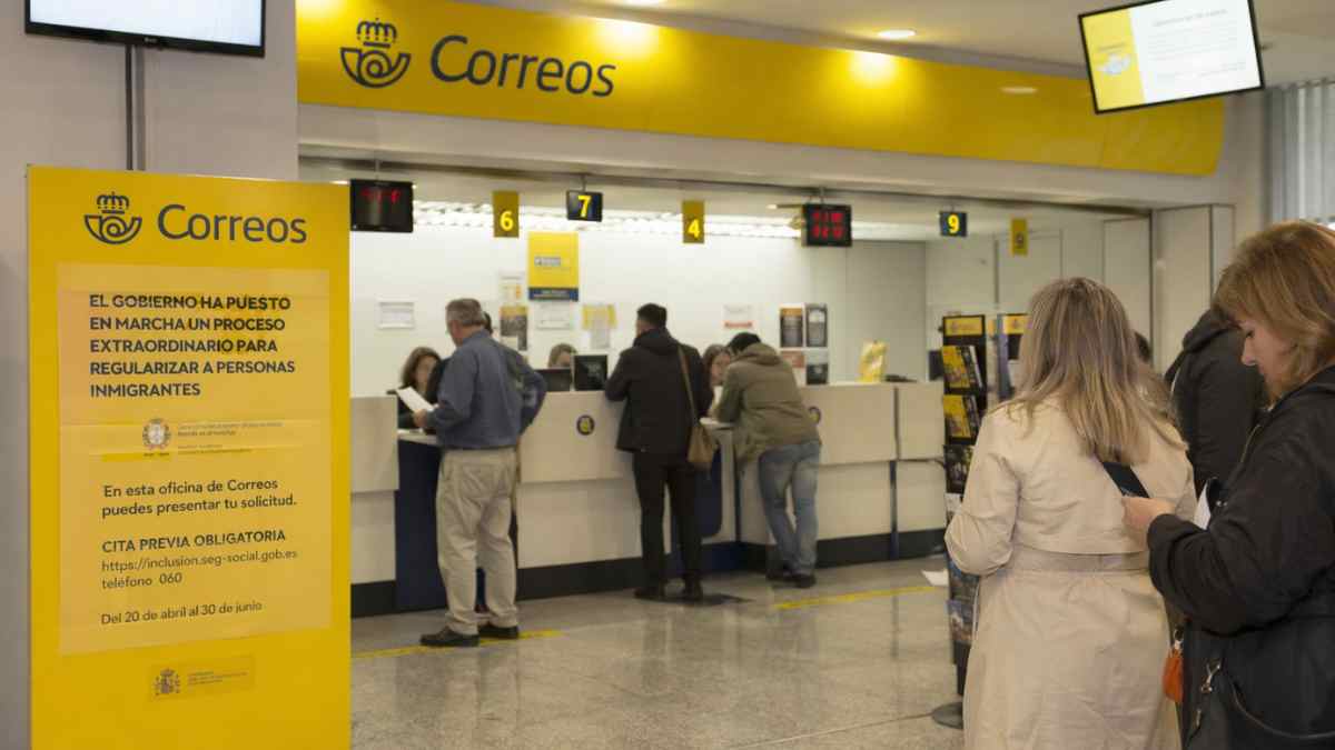 Oficina de Correos con personas presentando solicitud de regularización de inmigrantes con cita previa en España