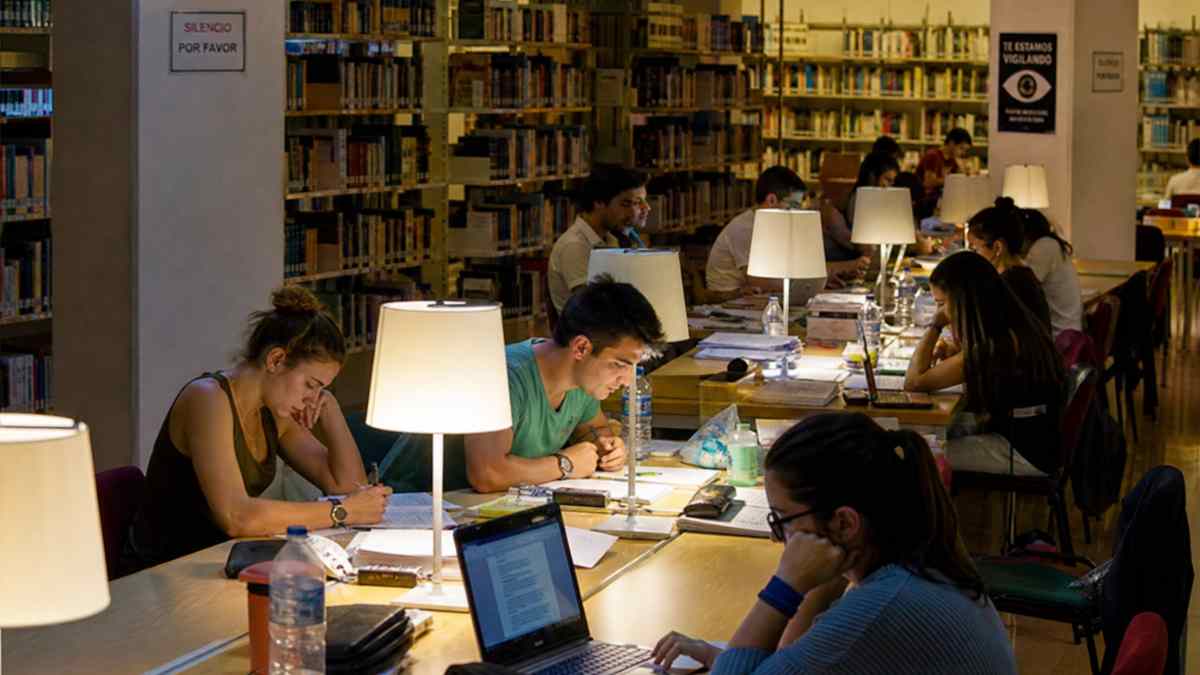 Estudiantes estudiando en biblioteca de Madrid con horario ampliado 24 horas durante época de exámenes