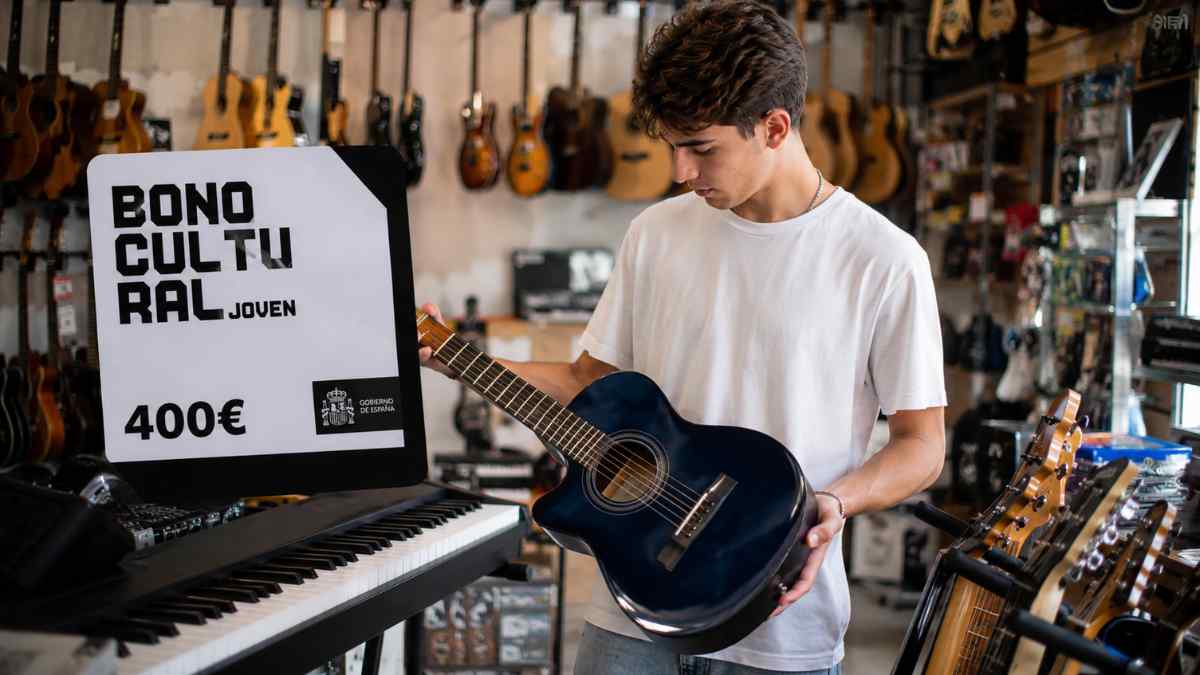 Joven comprando una guitarra con el Bono Cultural Joven de 400 euros en una tienda de instrumentos musicales