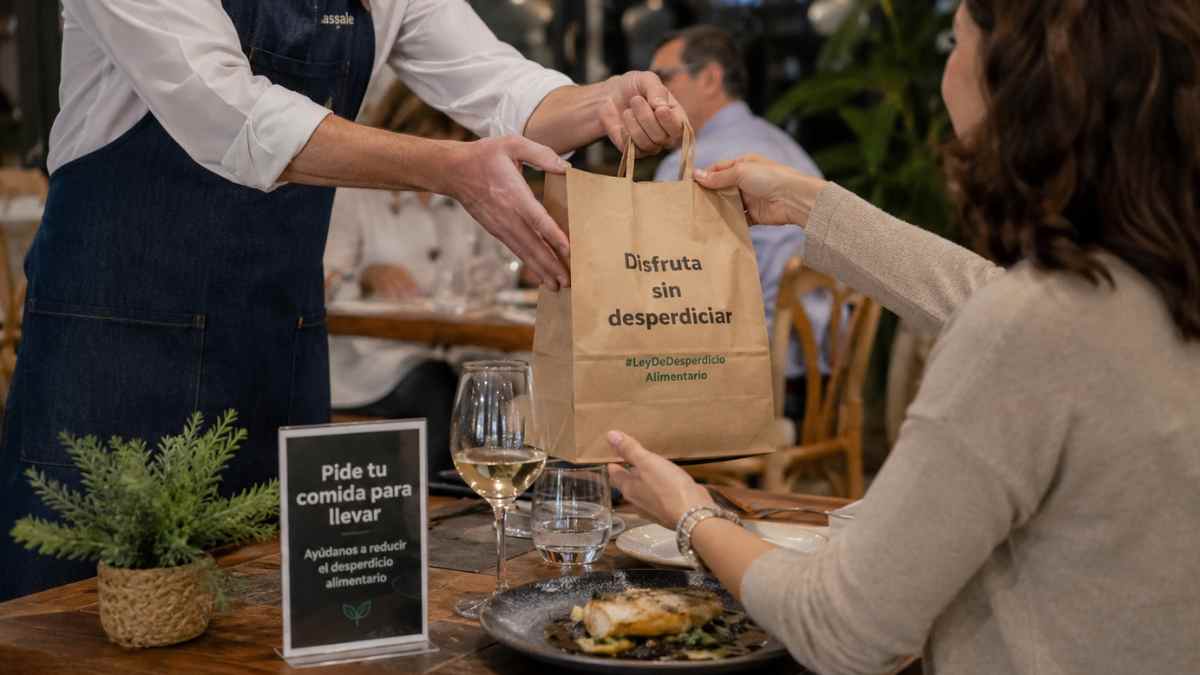 Camarero entrega comida sobrante para llevar en un restaurante por la Ley de Desperdicio Alimentario