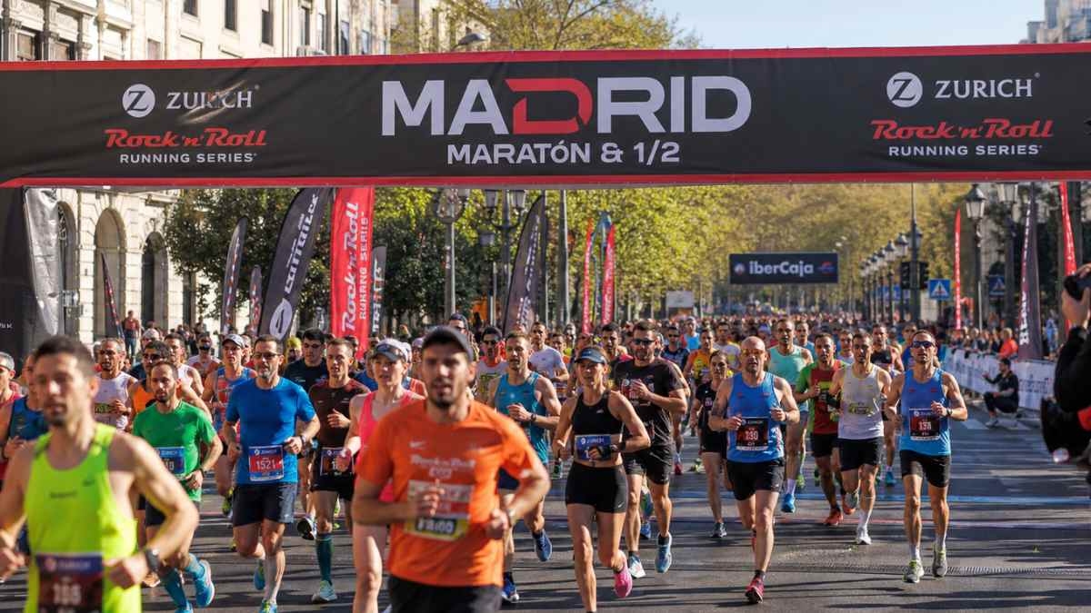 Maratón de Madrid 2027 con corredores saliendo bajo arco oficial durante la carrera en el centro de la ciudad