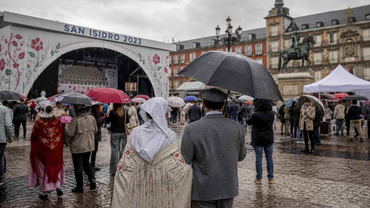 Personas con paraguas durante las fiestas de San Isidro en Madrid bajo la lluvia y el frío en la Plaza Mayor