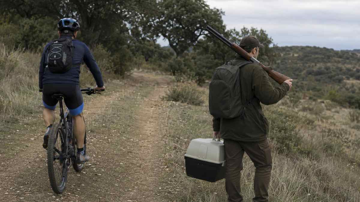 Trabajador agrícola de baja médica montando en bicicleta y cazando con escopeta durante una incapacidad temporal