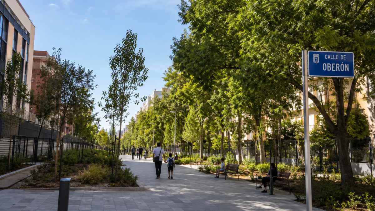 Calle de Oberón en Moratalaz tras su remodelación como vía peatonal con zonas verdes, árboles y mobiliario urbano en Madrid