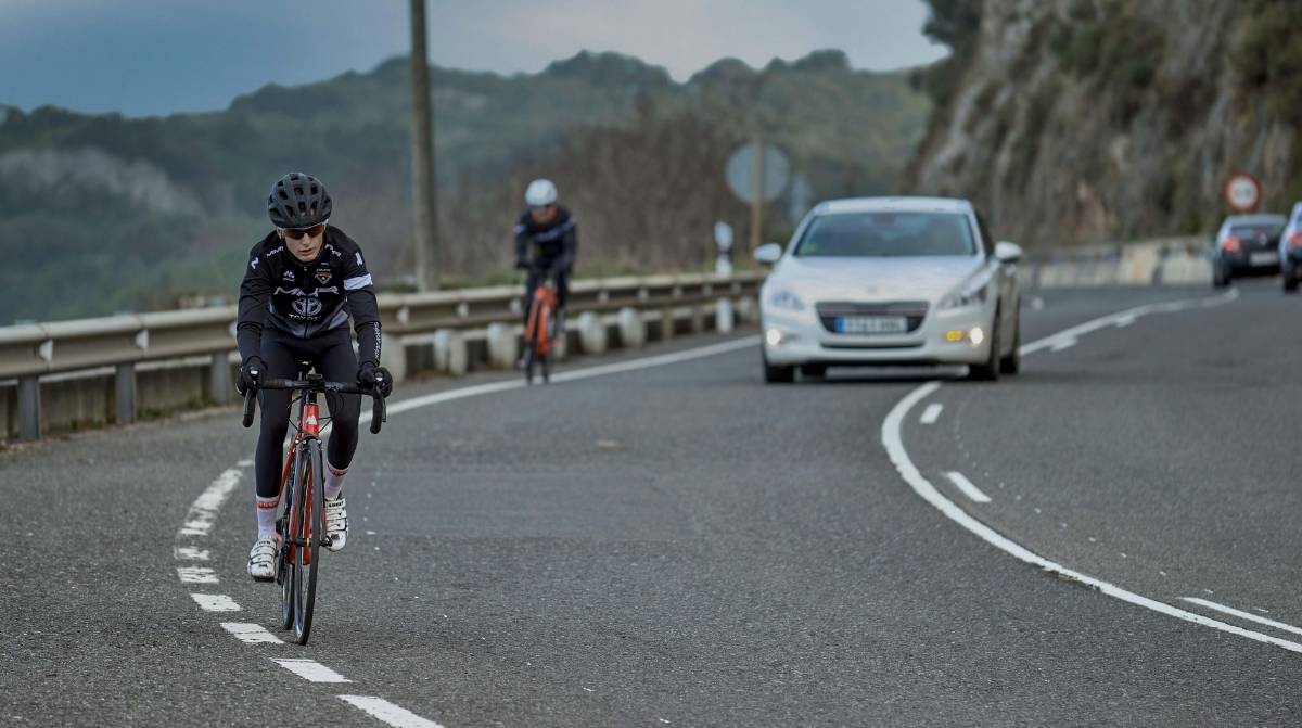 Ciclistas circulando por una carretera mientras un coche mantiene distancia de seguridad tras el cambio del Reglamento de Circulación.