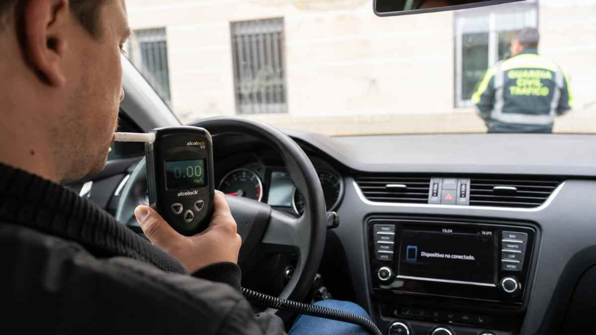 Conductor realizando una prueba con un alcolock o alcoholímetro antiarranque instalado en un coche para evitar conducir bajo los efectos del alcohol