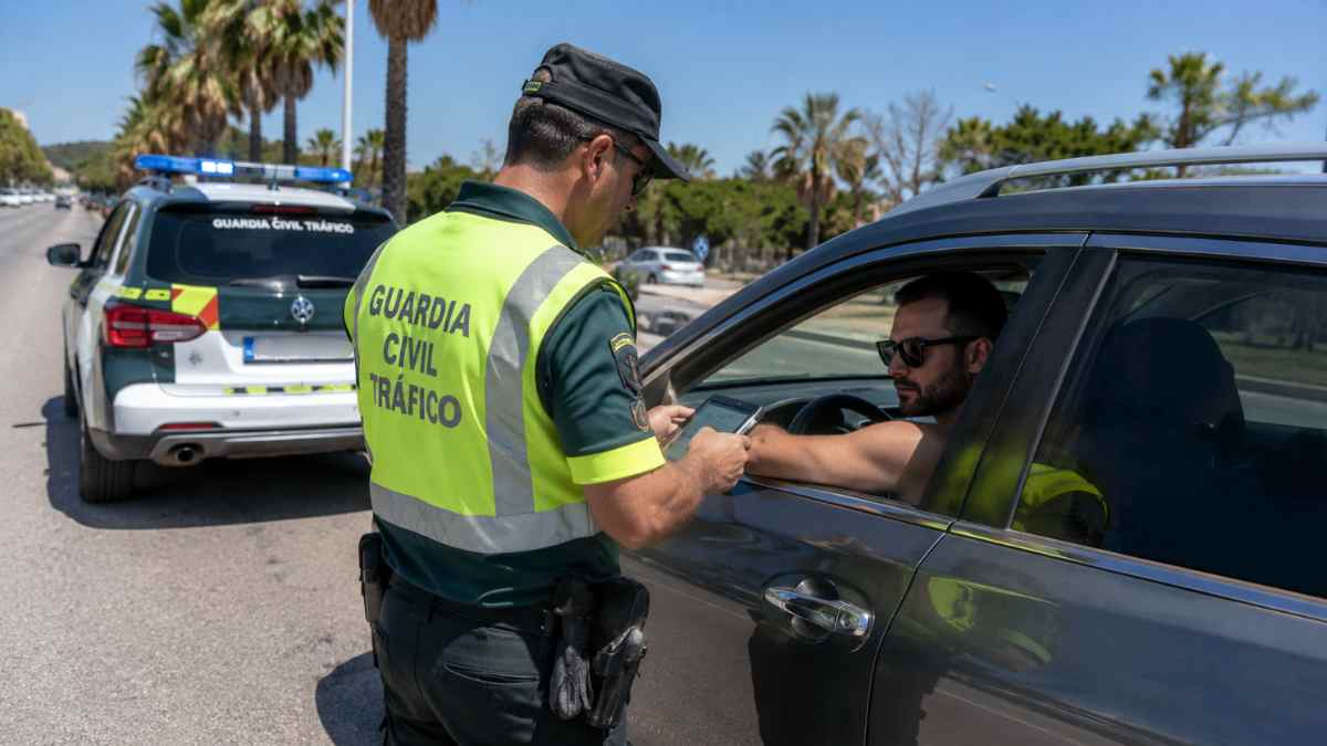 Agente de la Guardia Civil de Tráfico identifica a un conductor sin camiseta durante un control de carretera en verano