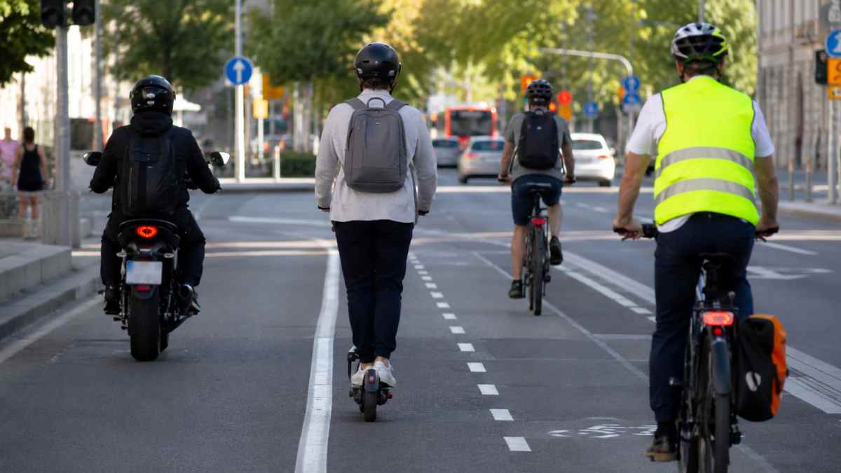 Patinete eléctrico, ciclistas y motorista circulando por una vía urbana tras los cambios de la DGT para usuarios vulnerables