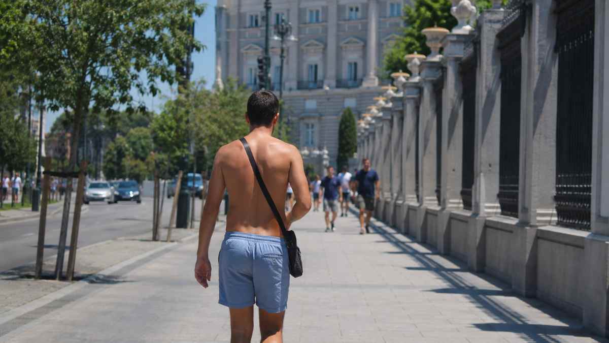 Hombre caminando sin camiseta por una calle de Madrid durante una jornada de calor en verano
