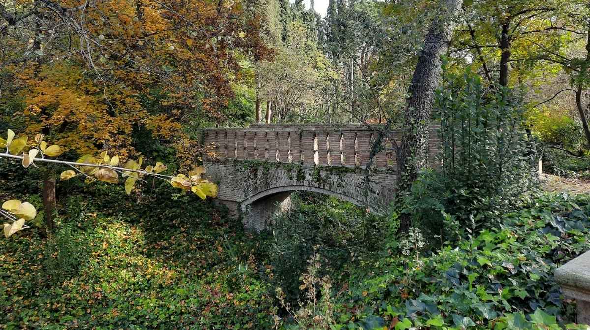 Puente histórico rodeado de vegetación en el parque de El Capricho de Madrid
