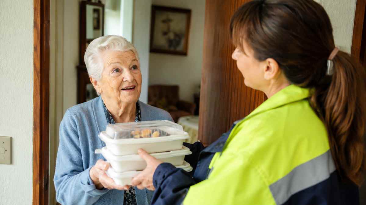 Persona mayor recibe un menú de comida a domicilio dentro del servicio municipal para mayores de Madrid