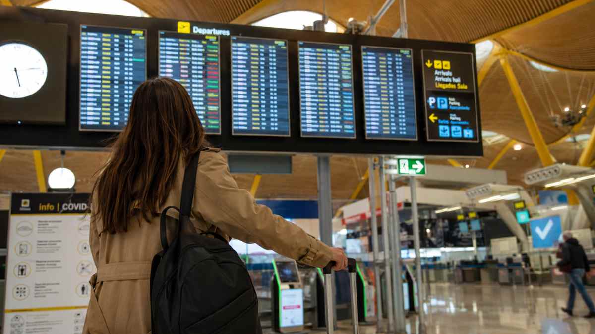 Pasajera consulta los paneles de vuelos en el aeropuerto Madrid-Barajas tras los nuevos derechos europeos para pasajeros aéreos