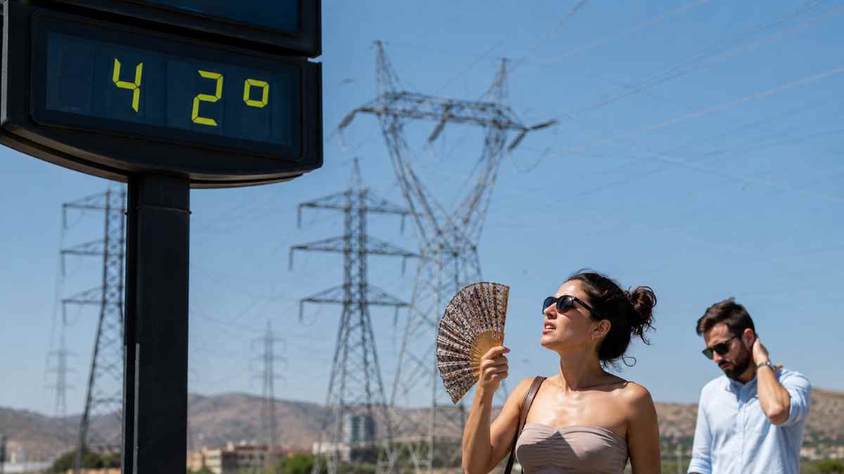 Personas soportando una ola de calor de 42 grados junto a torres eléctricas ante el riesgo de apagones en Europa