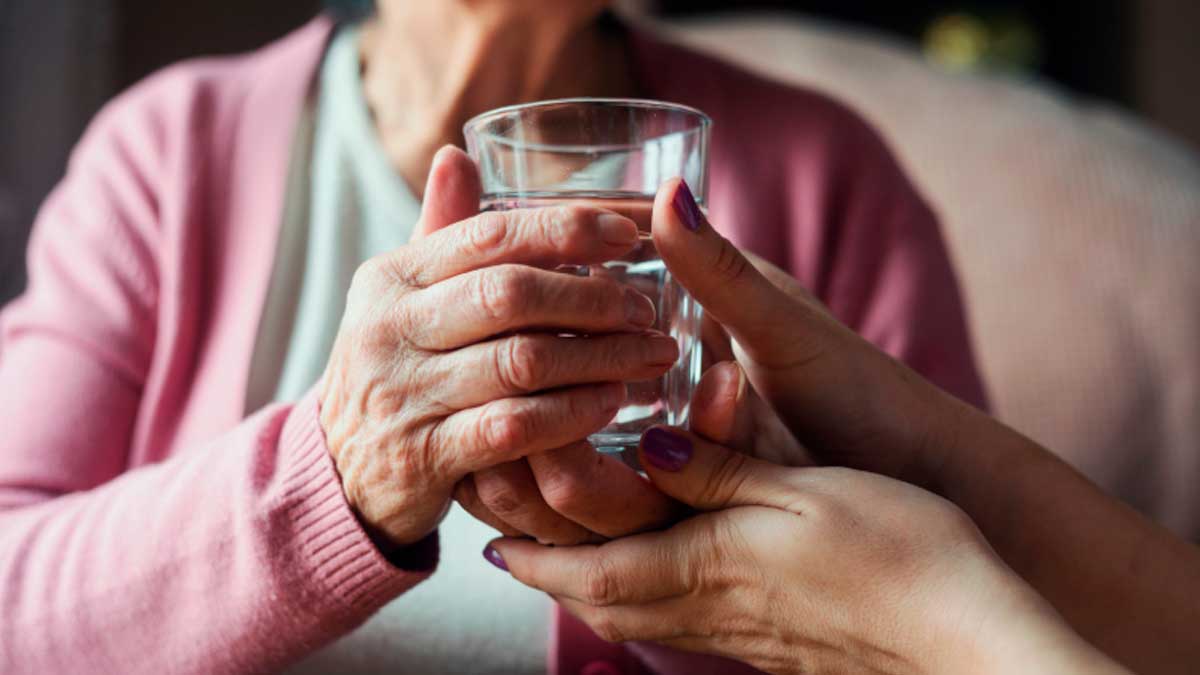 Persona mayor recibiendo ayuda para beber agua, dependencia en Madrid