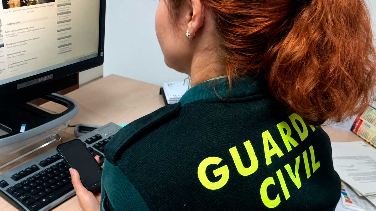 Agente de la Guardia Civil alerta sobre falsas donaciones por incendios en Madrid frente a un ordenador