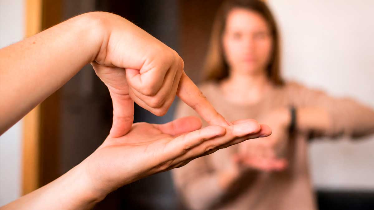 Persona usando lengua de signos en Madrid con intérprete al fondo