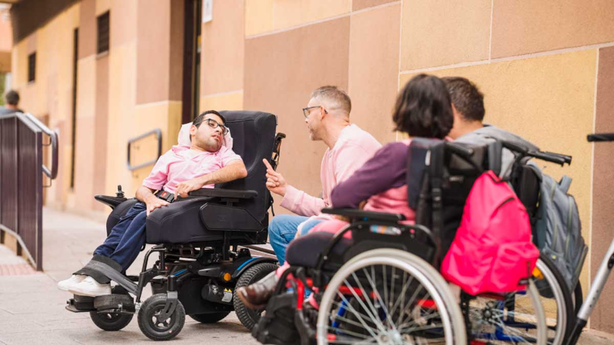Personas con discapacidad en silla de ruedas conversan frente a oficinas de vida independiente en Madrid