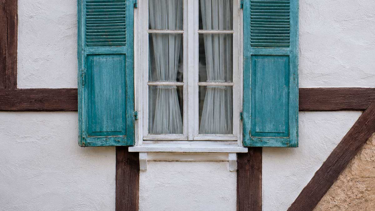 Ventana antigua con contraventanas verdes en vivienda típica andaluza rehabilitada energéticamente