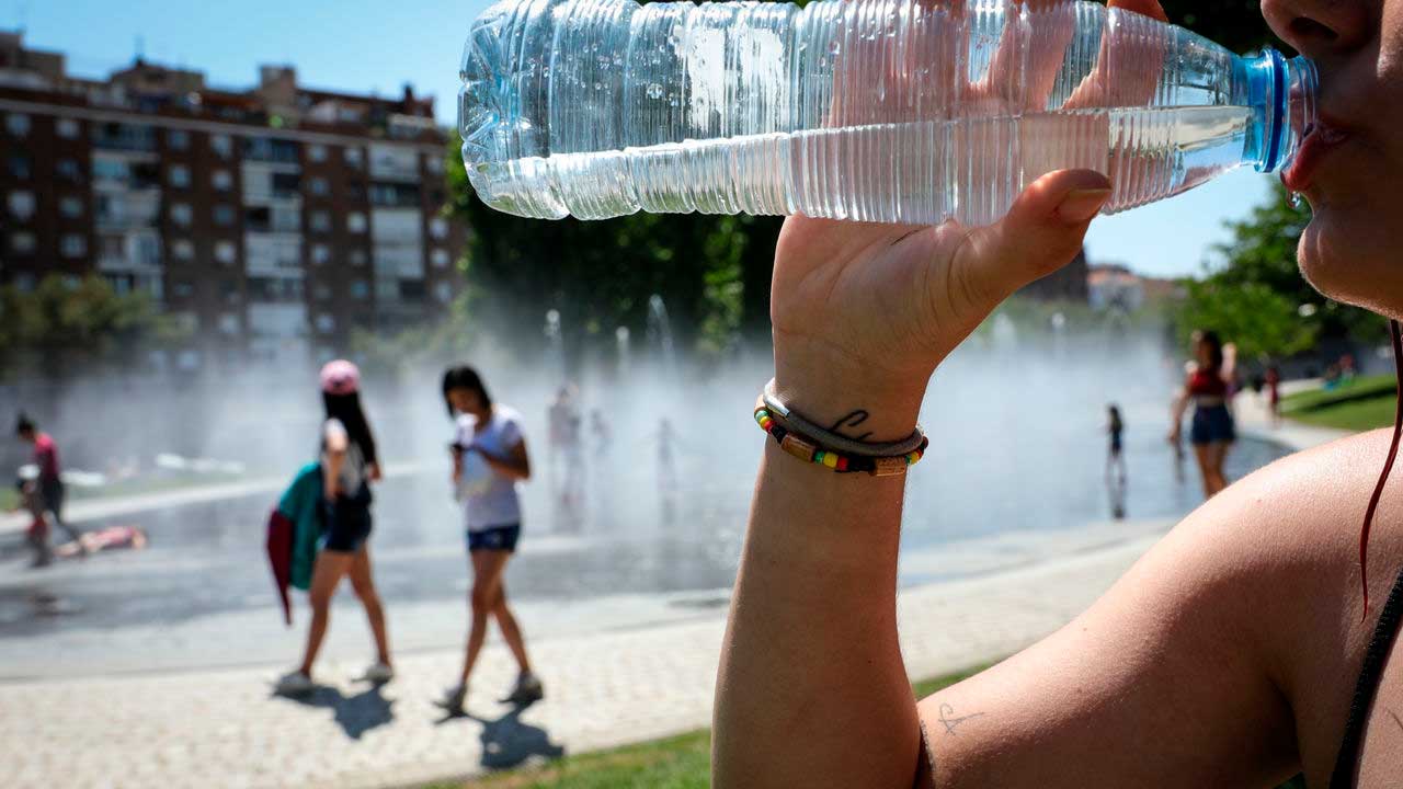 Mujer bebe agua durante un episodio de altas temperaturas en Madrid