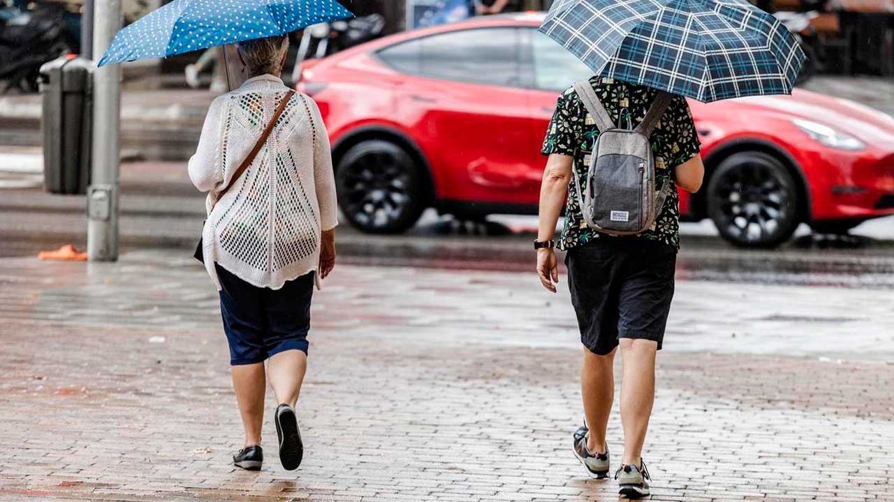 Dos personas caminan con paraguas bajo la lluvia en Madrid