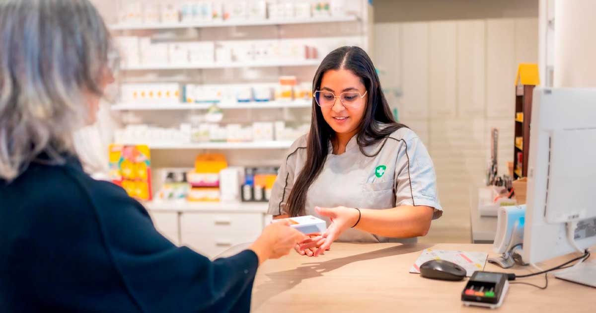 Farmacéutica entrega un medicamento a una paciente en una farmacia