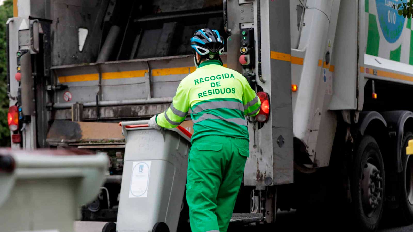 Trabajador de recogida de residuos junto a un camión de basura en Madrid