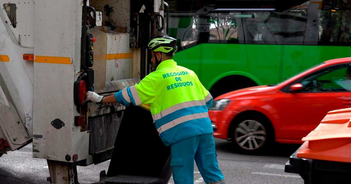 Operario de recogida de residuos en Madrid junto a un camión de basura