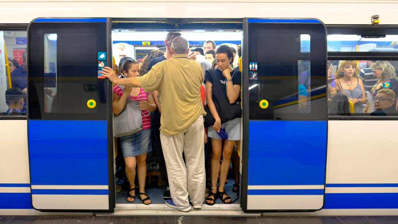 Viajeros en un vagón lleno de Metro de Madrid con las puertas abiertas