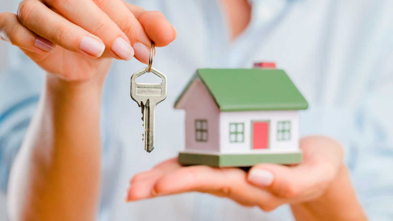 Una mujer sostiene las llaves y una maqueta de una casa, símbolo del alquiler con opción a compra de vivienda en Madrid