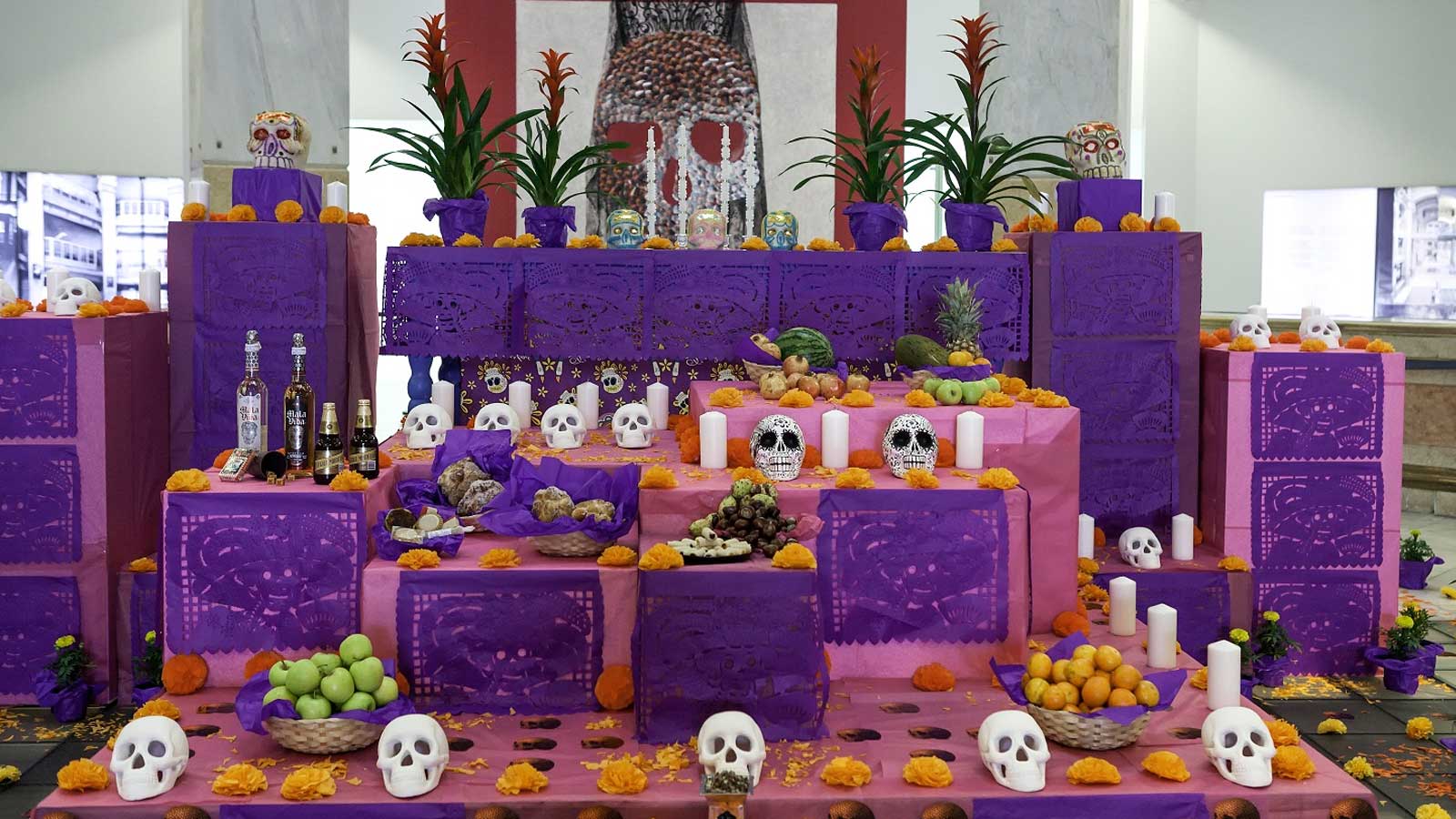 Altar de muertos en Madrid decorado con calaveras, flores naranjas, velas y ofrendas tradicionales mexicanas.