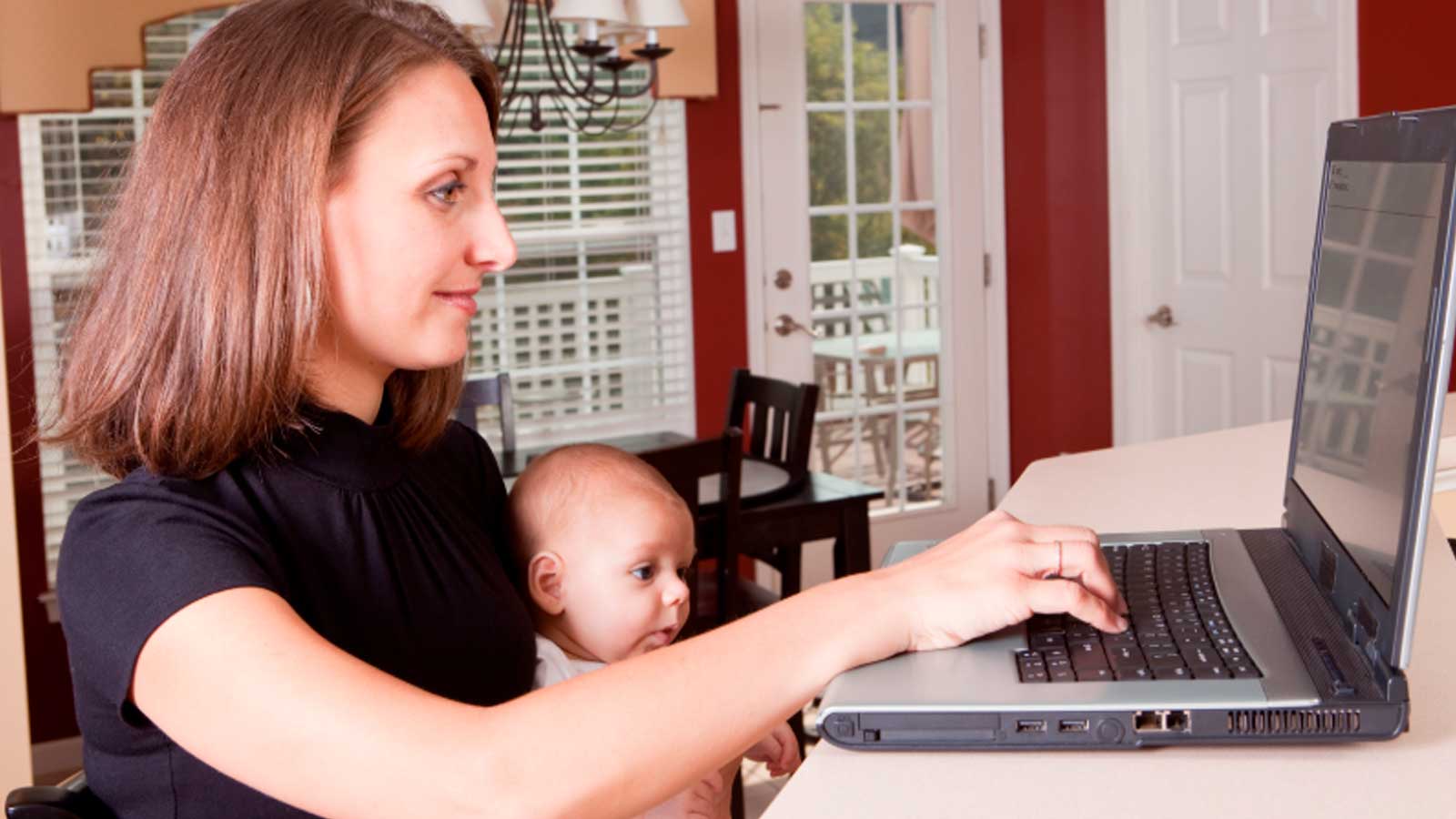 Mujer realizando un curso online mientras cuida de su hijo