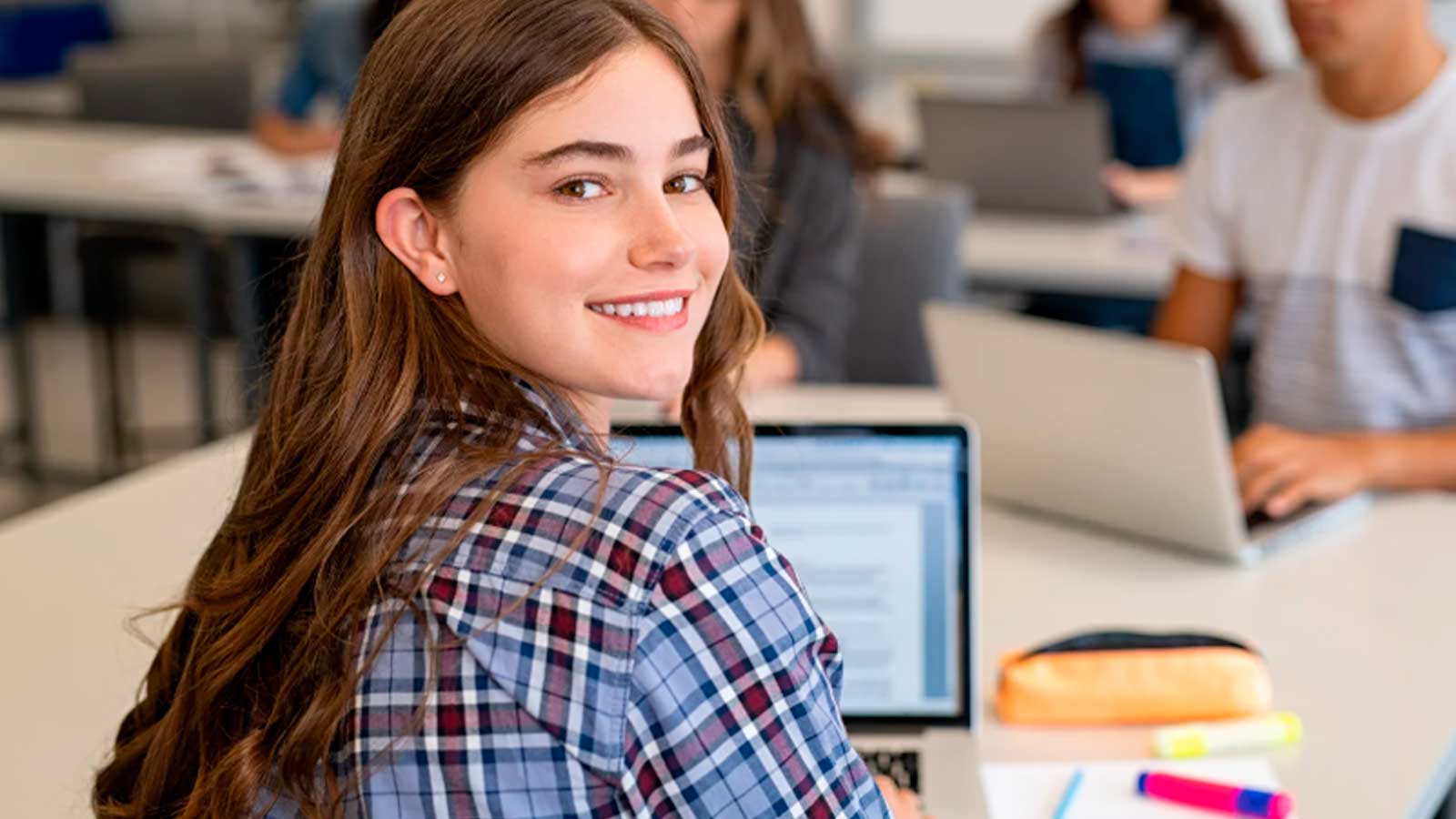 Estudiante universitaria en un aula con ordenador portátil durante una jornada de estudio.